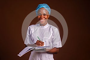 Closeup of a beautiful nurse smiling and taking notes on a brown background