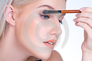 Closeup beautiful personable girl with flawless applying eye shadow makeup.