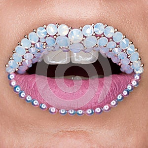 Closeup of beautiful pink lips with white gems and white teeth. Pink matt lipstick. Make-up, Cosmetics, lips art