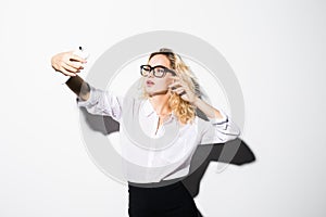 Closeup of beautiful playful business woman making selfie on isolated white background