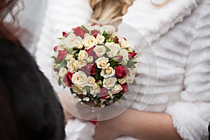 Closeup of a beautiful romantic pink and red roses wedding bouquet in brides hands