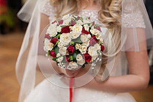 Closeup of a beautiful romantic pink and red roses wedding bouquet in brides hands