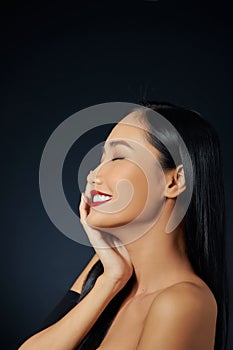Closeup of beautiful smiling woman touching soft smooth facial skin