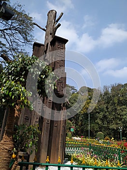 Closeup of beautiful tall wooden art in front of the Chama Raja Wadiyar statue at Cubbon Park