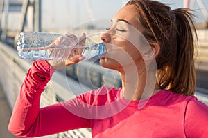 Closeup of a beautiful woman drinking water outside after training