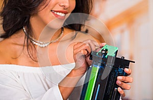 Closeup of a beautiful woman fixing a photocopier and smiling during maintenance repairs using handheld tool
