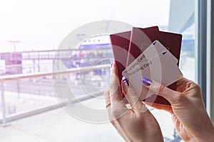 Closeup of beautiful woman hand holding passports and boarding pass tickets at airport terminal. Travel and holiday concept. Termi