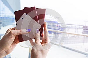 Closeup of beautiful woman hand holding passports and boarding pass tickets at airport terminal. Travel and holiday concept. Termi