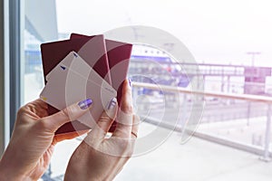 Closeup of beautiful woman hand holding passports and boarding pass tickets at airport terminal. Travel and holiday concept. Termi