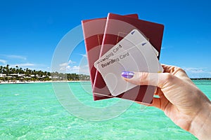 Closeup of beautiful woman hand holding passports and boarding pass tickets at the tropical beach. Travel and holiday concept. Emp
