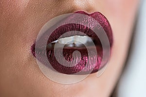 Closeup of beautiful woman lips with purple lipstick. Open mouth with white teeth. Cosmetics, lip gloss