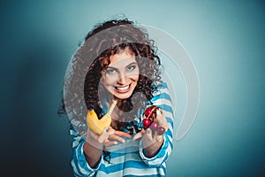 Closeup beautiful woman showing giving to eat banana or cherry fruits isolated blue background wall. Healthy lifestyle concept