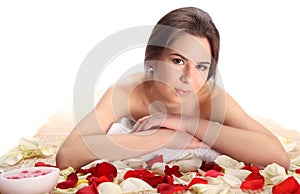 Closeup Beautiful, young and healthy woman in spa salon on bamboo mat with rose petals. Spa, health and healing concept.