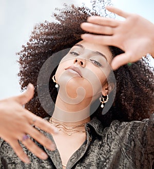 Closeup of a beautiful young mixed race woman with an afro framing her face with her hands. Looking for the perfectly