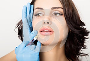 Closeup of Beautiful young woman gets injection in eye and lips area from beautician. cosmetology concept