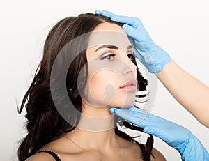 Closeup of Beautiful young woman gets injection in eye and lips area from beautician. cosmetology concept