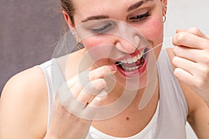 Closeup of beautiful young woman using dental floss for healthcare