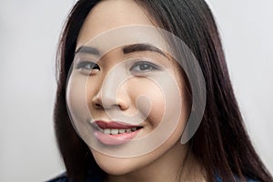 Closeup beauty portrait of beautiful brunette asian young woman with makeup, straight dark hair standing and looking at camera