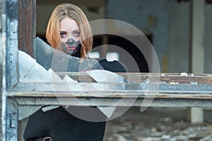 Closeup beauty portrait of a beautiful girl in a black mask with rhinestones, makeup designer. Looking out from a broken window.