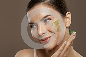 Closeup beauty portrait of cheerful woman with herbal face cream on skin. Facial treatment