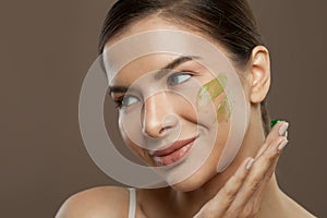Closeup beauty portrait of cheerful woman with herbal face cream on skin. Facial treatment