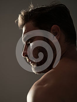 Closeup beauty portrait of satisfied young man after facial cream. Attractive brunet guy touching skin. Men model face