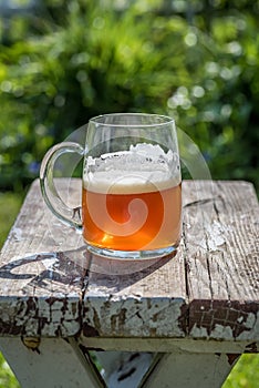 Closeup of a beer mug on old wood table top in sunlight