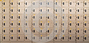 Closeup beige locker with lock and numbered yellow tags at locker room. Locker for safety and security storage. Row of locker with