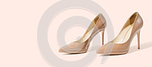 Closeup beige women patent leather shoes isolated on pink background. Stilettos shoe type. Summer fashion and shopping concept.