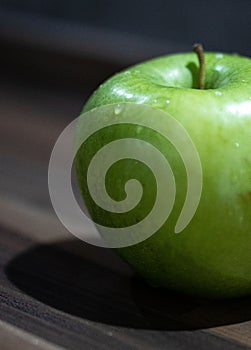 Closeup of a big green apple covered with water droplets