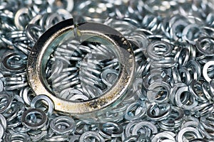 Closeup of big steel spring lock washer on texture of small stainless split washers heap