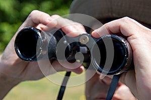 A closeup of the binoculars held by man.