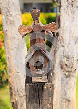 Closeup of bird wood house with gable roof and windmill in the g