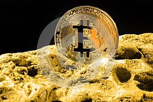 Closeup of bitcoin digital currency and gold nugget or gold ore on black background, precious stone or lump of golden