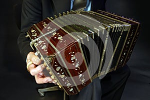 a closeup of a black bandoneon in the process of playing