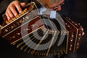 a closeup of a black bandoneon in the process of playing