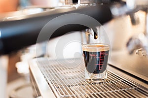 Closeup black coffee in measuring cup put on coffee maker,coffee machine making espresso