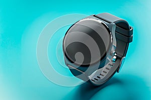 Closeup of black digital smart wrist watch with blank screen on turquoise background