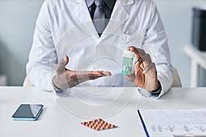 Closeup black doctor holding bottle of pills