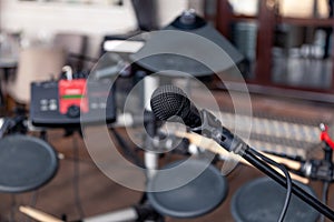 Closeup black iron microphone stands on stage background of installation of musical cymbals. Concept live concert in bar in