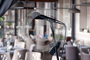 Closeup black iron microphone stands on stage background of restaurant hall served for banquet. Concept live music concert in bar