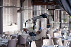 Closeup black iron microphone stands on stage background of restaurant hall served for banquet. Concept live music concert in bar