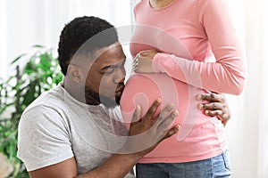 Closeup of black man kissing his pregnant wife belly