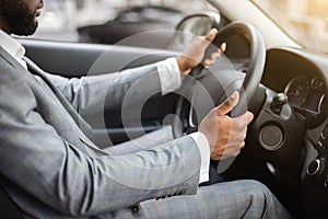 Closeup of black man in suit driving car