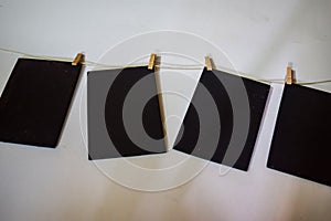 Closeup black paper attach to rope with clothes pins on white background