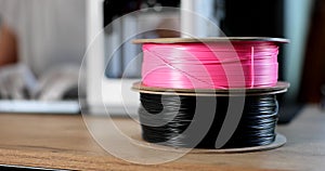 Closeup of black and pink spools of plastic for 3D printer 4k movie slow motion