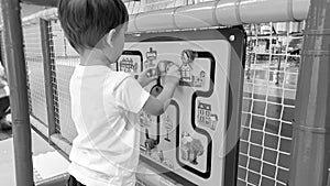 Closeup black and white portrait of adorable toddler boy playing with wooden toy puzzle on the children palyground