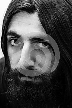 Closeup black-and-white portrait of a bearded man with long hair.