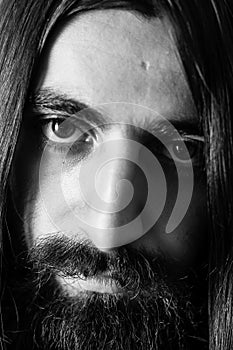 Closeup black-and-white portrait of a bearded man with long hair.