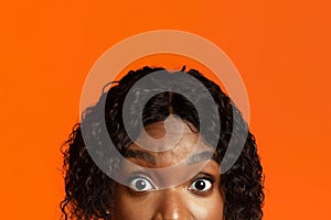 Closeup of black woman surprised eyes, orange background